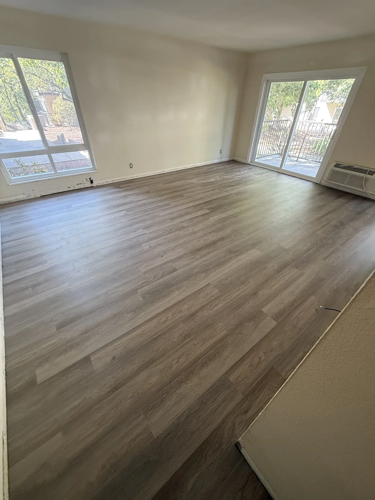 Completed wood-look flooring in an Oak Creek living area beside windows and a sliding glass door