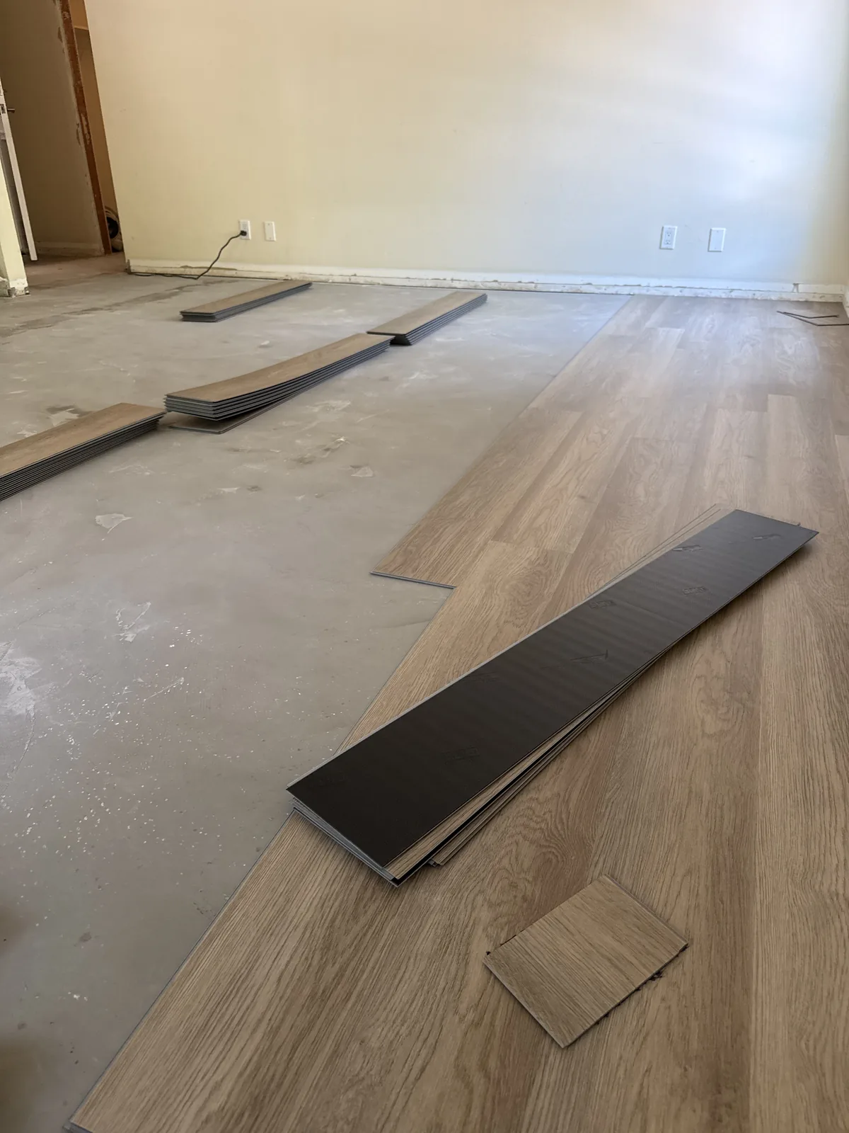 Wood-look planks being laid beside exposed subfloor in an Oak Creek apartment