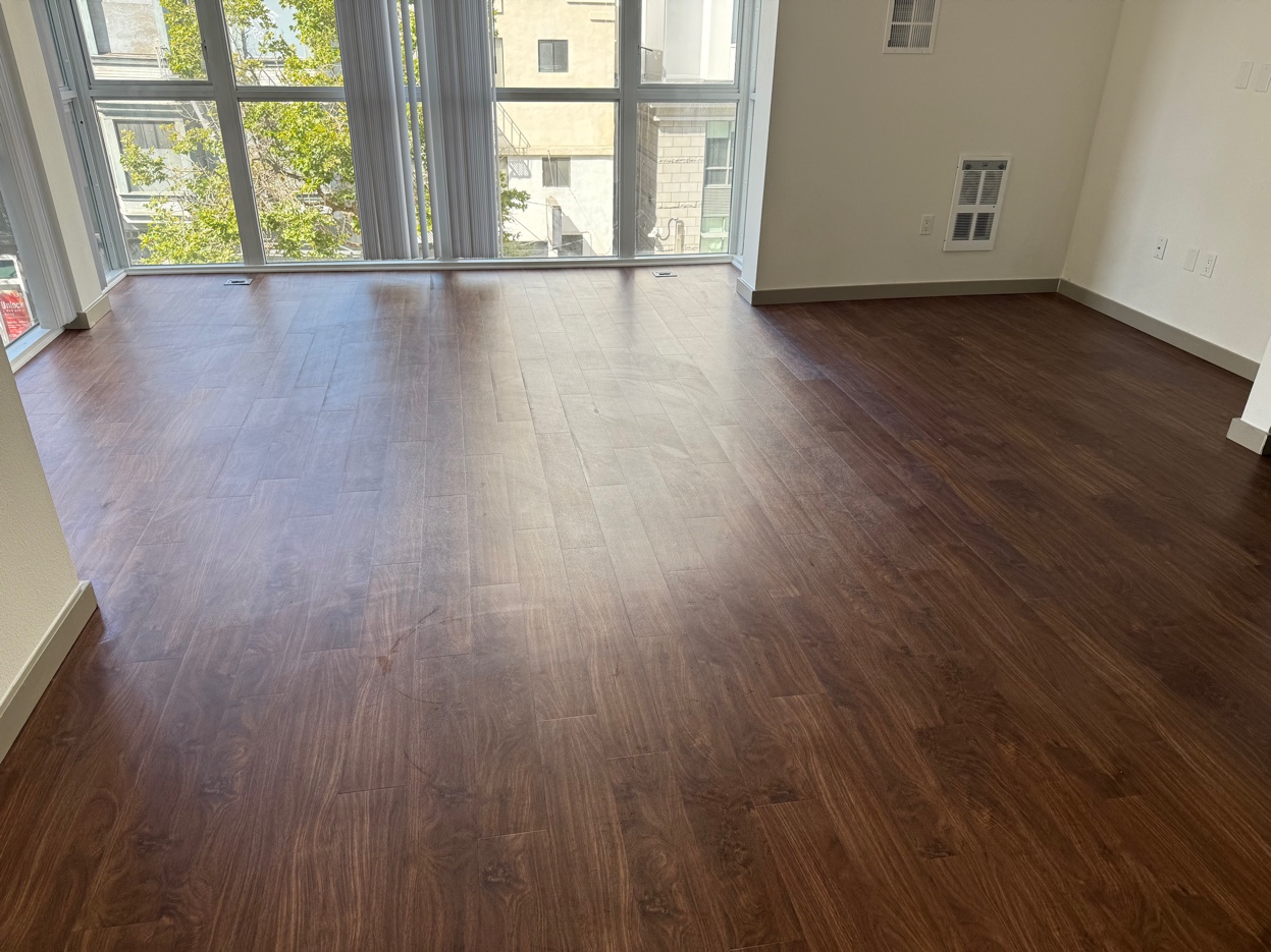 Warm wood-look LVT flooring installed by Copala Floors in an apartment with large windows