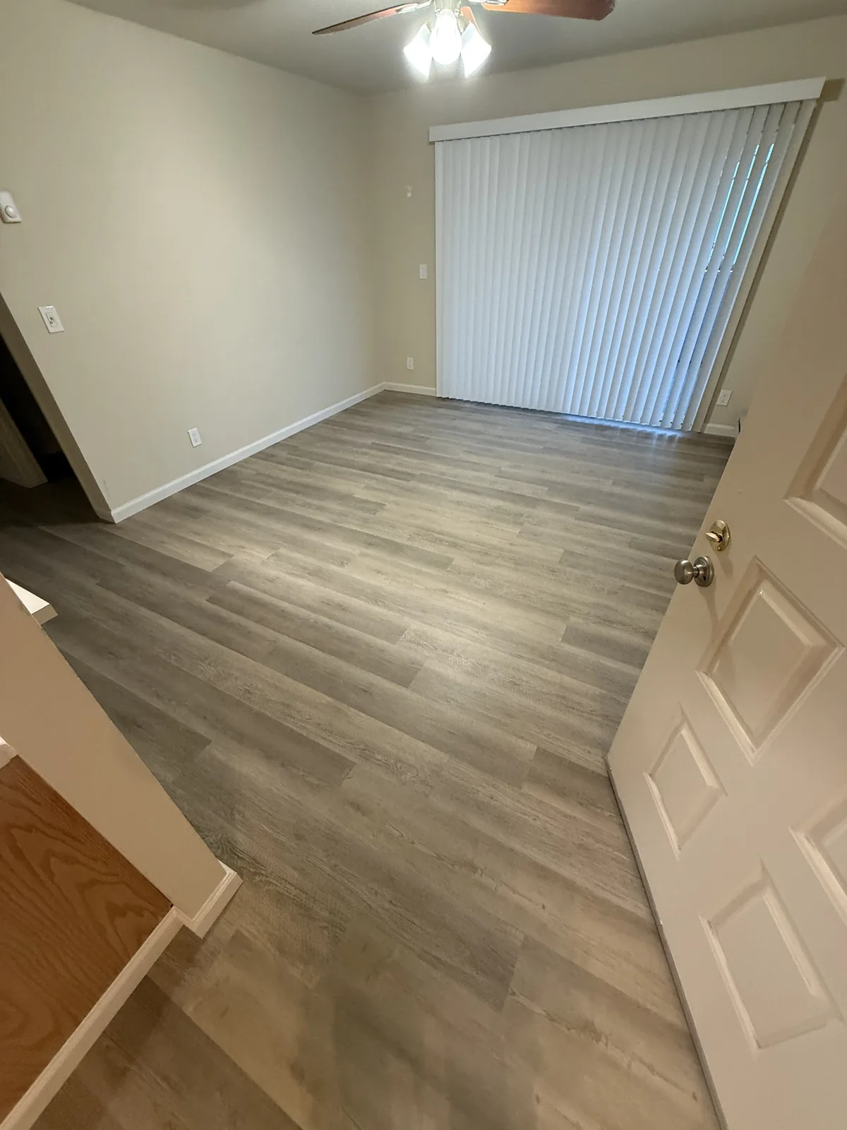 Completed light wood-look flooring in a Windermere living area beside a sliding glass door