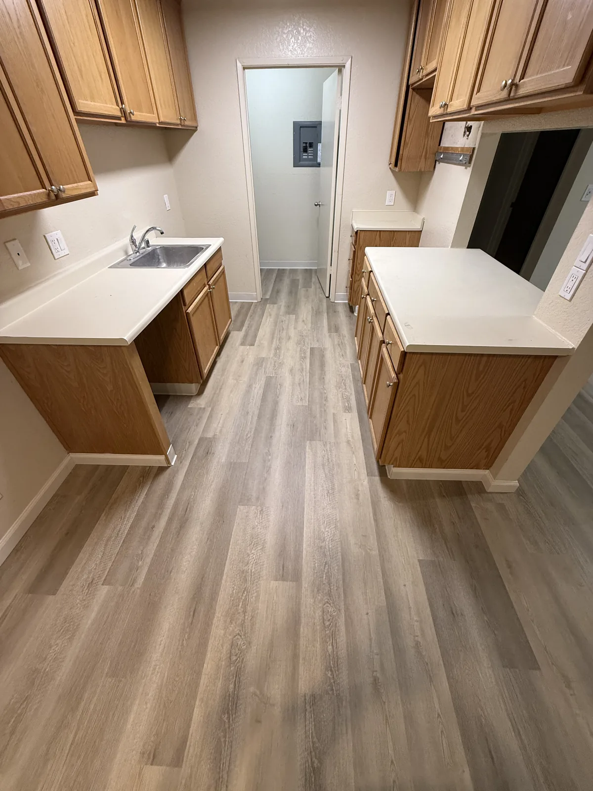 Completed wood-look flooring through a Windermere galley kitchen with wood cabinets