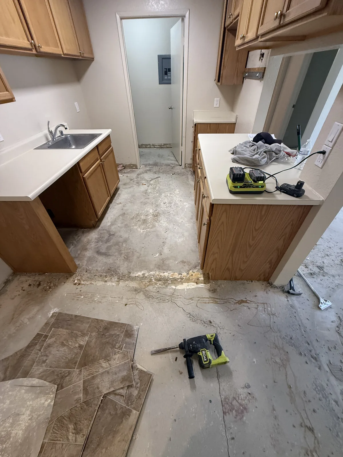 Exposed kitchen subfloor with tools and removed flooring pieces at Windermere