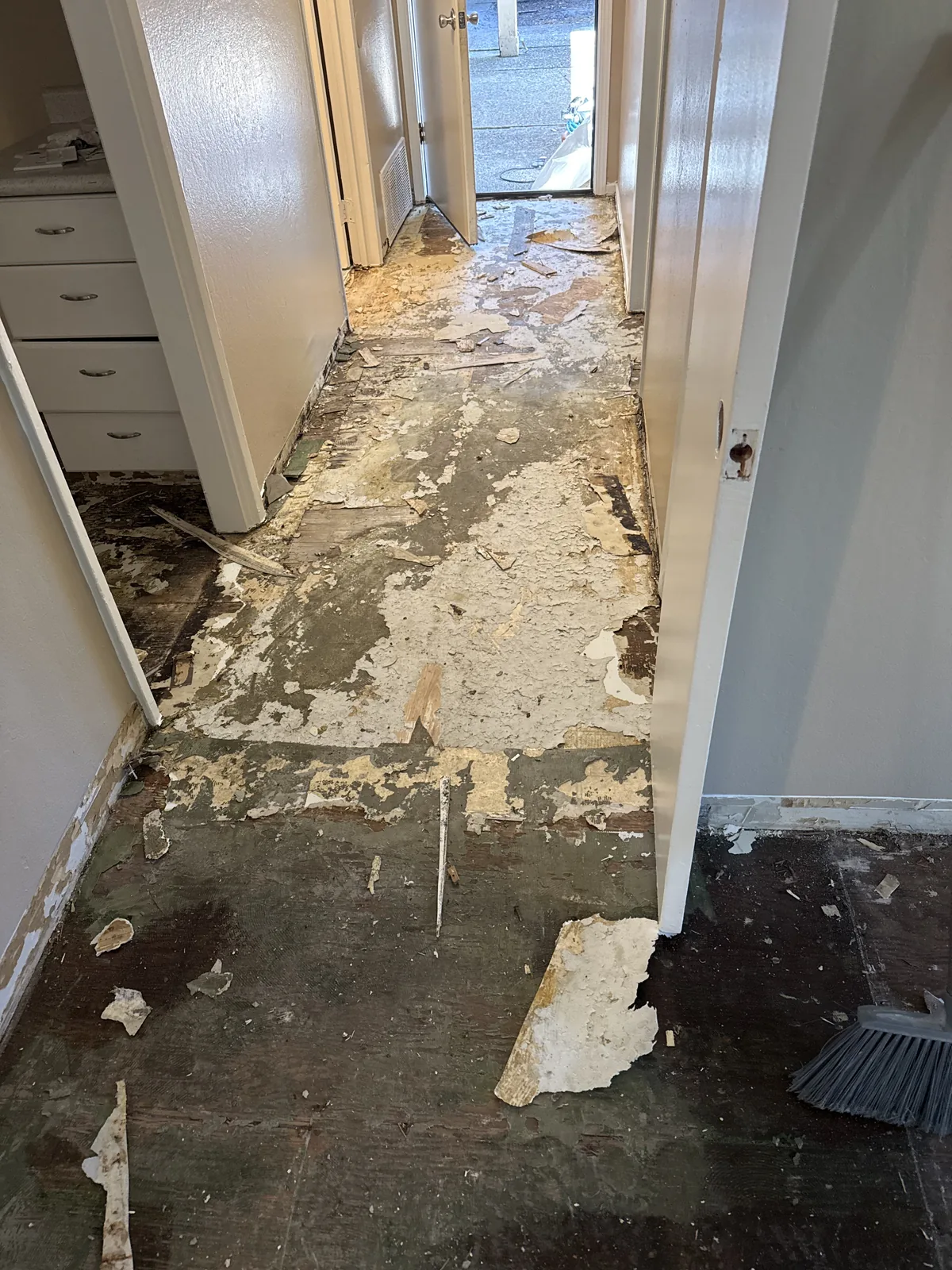 Exposed subfloor and flooring removal remnants along a Woodland Park apartment hallway